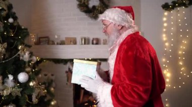 Komik Noel Baba sinsice yaklaşır ve Noel ağacının altına yeni yıl hediyesi koyar. Noel 'den önceki Aralık Akşamı. Yeni yıl rüya konseri Noel ruhu.