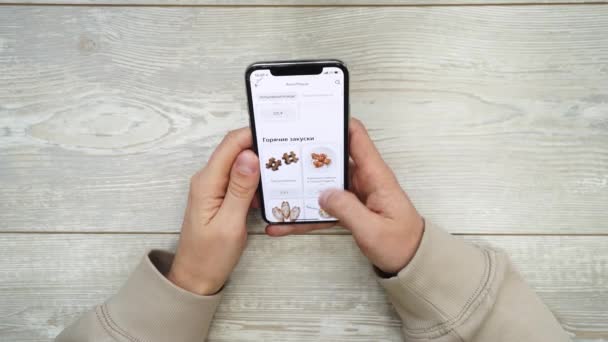 Bestillinger Fødevarer Brug Online Levering. Man Ordrer Mad Hjem I Online Store Ved hjælp af en smartphone. Mandlig Bestilling pizza ved hjælp af mad levering app. – Stock-video