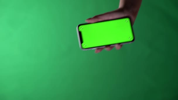 Rusko. Moskva. 8. prosince2020. Žena ruka drží smartphone na zeleném pozadí obrazovky chroma klíč. Model mobilního telefonu pro váš produkt. — Stock video