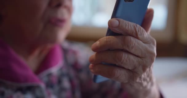 Närbild av gamla mormor med en telefon i händerna. En gammal mormor talar genom videolänk med sina släktingar i närbild Lycklig gammal kvinna talar via videolänk med familjen på grund av social — Stockvideo