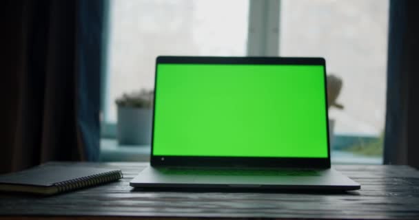 Dolly betolja a laptopot, zöld képernyővel az asztalon, az ablakok előtt, függönyökkel. A távoli virtuális távoktatás koncepciója