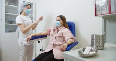 Güvenlik Eldiveni ve Koruyucu Maske Hemşiresi, Sağlık Kliniğindeki Kadın Hastaya Aşı Yapıyor. Doktor şırınga ve şırıngayla ilaç iğnesini tedavi olarak kullanıyor.