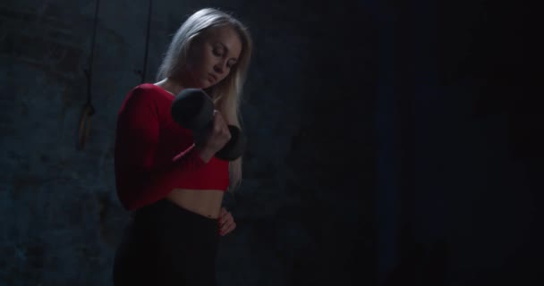 Pretty Athletic Female gör fitness i det moderna gymmet. Bottenvy, brett skott, atletisk ung kvinna i sportkläder lyfta hantlar från golvet i mörk loft interiör. — Stockvideo