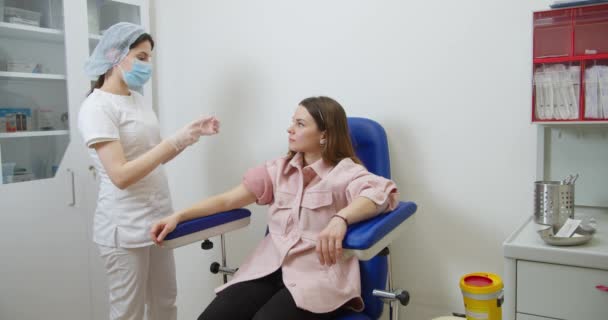 Asistenta medicală în mănuși de siguranță și mască de protecție face o injecție de vaccin la o pacientă de sex feminin într-o clinică de sănătate. Medicul folosește acul hipodermic și o seringă pentru a pune o doză de medicament ca tratament — Videoclip de stoc