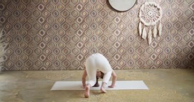 Genç bir kadın yoga yaparken dengesini koruyor. Spor düşkünü kız sabahları atmosferik yoga odasında yoga yapıyor.