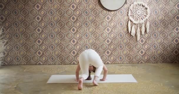 Ung kvinna som håller balansen och gör ett yogahuvud stående. Sportig smal tjej som gör yoga i ett ljust, stämningsfullt yogarum på morgonen — Stockvideo