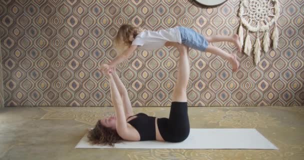 Moderno niño familiar feliz y saludable hijo y madre joven que se divierten haciendo ejercicios de yoga juntos, mamá consciente sonriente enseñando a un niño lindo a meditar en el estudio de yoga — Vídeos de Stock