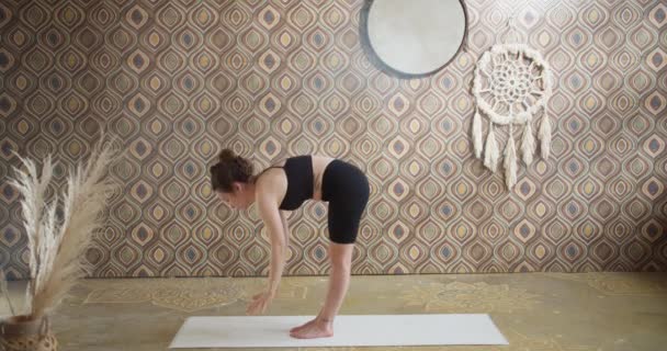 Sportovní kudrnaté vlasy žena dělá jóga strečink cvičení. Štíhlá dívka dělá jógu v jasném, atmosférickém pokoji jógy ráno — Stock video