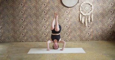 Genç bir kadın yoga yaparken dengesini koruyor. Spor düşkünü kız sabahları atmosferik yoga odasında yoga yapıyor.