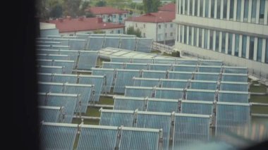 Endüstriyel binanın çatısında güneş pilleri var. Çatıdaki fotovoltaik güneş panelleri güneşten temiz enerji alıyor. Ağır çekim. Hava görünümü.