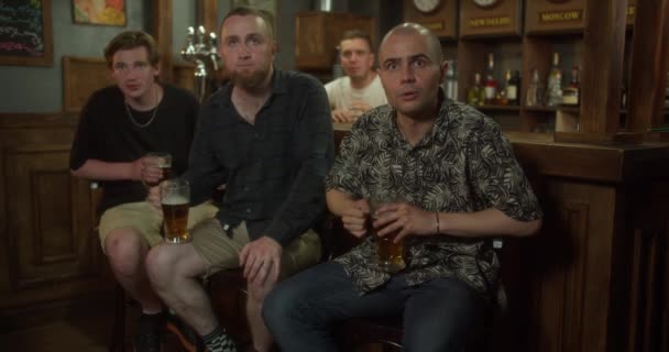 Skupina mužských přátel fanoušci s barman slaví při sledování hry na televizní obrazovce ve sportovním baru. — Stock video