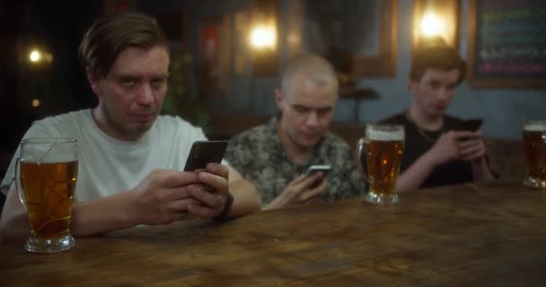 Hombre ansioso comprobar las apuestas en el teléfono celular, viendo deportes en el bar, aplicación de corredor de apuestas. Los fans celebrando mientras ven el juego en la pantalla de TV en el bar deportivo — Vídeo de stock