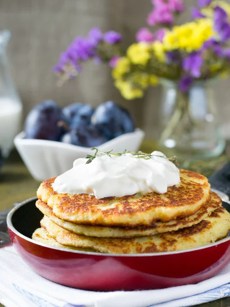 Potato pancakes in a pan with sour cream — Stock Photo, Image