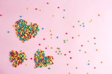 Pembe arka planda çok renkli yıldızlardan yapılmış bir kalp. Renkli sevgililer günü
