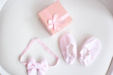 Pembe kurdeleli bebek botları ve arka planda hediye kutusu.