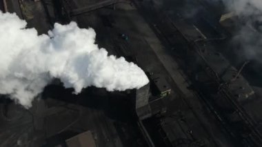 Drone fly around toxic enterprise chimneys tubing against the sky background release smoke. Factory pollutes environment. Aerial view. Ecology disaster. Azovstal. Mariupol, Ukraine