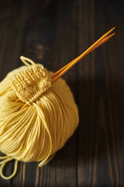 İlk örgü projesine başlıyorum. Sarı örgü ipliği ve ahşap arka planda iğneler