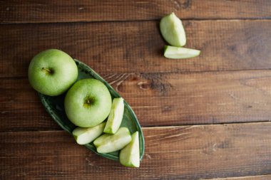 Ahşap arka planda yeşil elmalar. Kapatın. Sağlıklı gıda kavramı. Kesme tahtasında dilimlenmiş yeşil elma