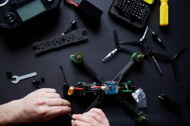 İnsanoğlunun ellerinin parçalardan bir FPV dronu monte ederken, aletleri kullanarak, yüksek hızlı yarış kuadkopterini uçuş için hazırlarken kapanmasını. Eğitim sürecinden önce İHA 'yı onar.