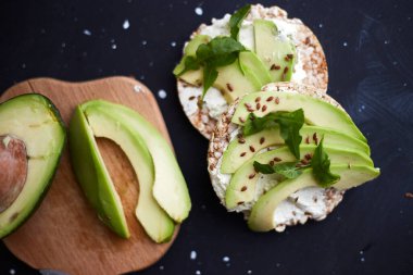 Fresh crisp bread with cream cheese, avocado and seeds on a black background. Vegetarian and diet food. Weight loss diet