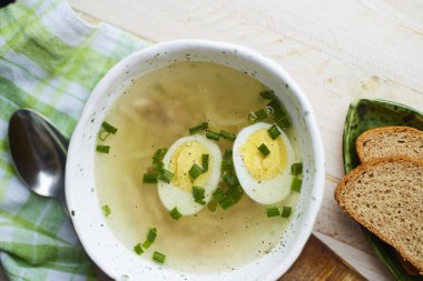 Tavuk çorbası, haşlanmış yumurta ve taze yeşil soğanlı el yapımı seramik kase..  