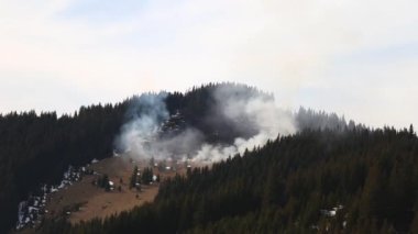 Dağlarda orman ve tarla yanıyor. Kuru otlar ilkbaharın başında yanar, doğal afet. Yanacak çok yeri olan büyük bir alan yangını. Yanan yerlerden dumanlar yükseliyor.