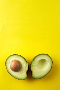 Avokado yarıları sarı arka planda. Tohumlu organik avokado. Boşluğu kopyala