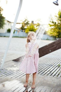 Plaj duşuyla oynayan duygusal komik kız. Sıcak yaz günü. Yaz alıntıları