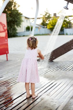 Plaj duşuyla oynayan duygusal komik kız. Sıcak yaz günü. Yaz alıntıları