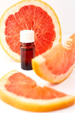 Beyaz arka planda taze greyfurtla cam şişede bulunan turunç ya da greyfurt yağı. Spa ve cilt ürünleri