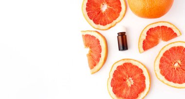Beyaz arka planda taze greyfurtla cam şişede bulunan turunç ya da greyfurt yağı. Spa ve cilt ürünleri
