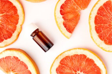 Beyaz arka planda taze greyfurtla cam şişede bulunan turunç ya da greyfurt yağı. Spa ve cilt ürünleri