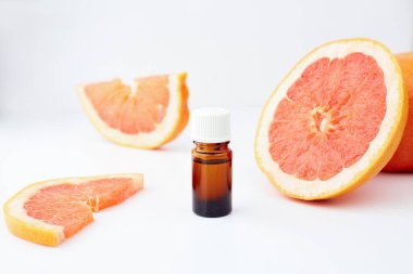 Beyaz arka planda taze greyfurtla cam şişede bulunan turunç ya da greyfurt yağı. Spa ve cilt ürünleri