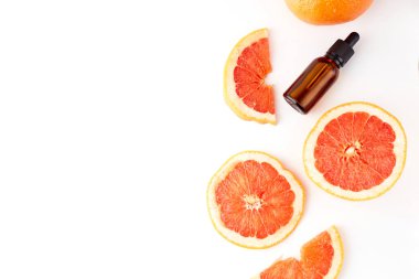 Beyaz arka planda taze greyfurtla cam şişede bulunan turunç ya da greyfurt yağı. Spa ve cilt ürünleri