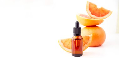 Beyaz arka planda taze greyfurtla cam şişede bulunan turunç ya da greyfurt yağı. Spa ve cilt ürünleri