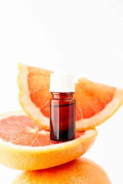 Beyaz arka planda taze greyfurtla cam şişede bulunan turunç ya da greyfurt yağı. Spa ve cilt ürünleri