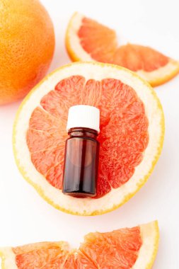 Beyaz arka planda taze greyfurtla cam şişede bulunan turunç ya da greyfurt yağı. Spa ve cilt ürünleri