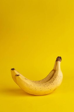 Kahverengi noktalı gerçek muzlar ve sarı arka planda boşluklar. Dikey afiş. Metin için boşluk