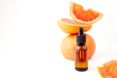 Beyaz arka planda taze greyfurtla cam şişede bulunan turunç ya da greyfurt yağı. Spa ve cilt ürünleri
