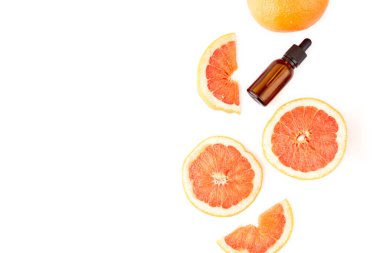 Beyaz arka planda taze greyfurtla cam şişede bulunan turunç ya da greyfurt yağı. Spa ve cilt ürünleri