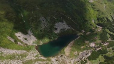 Aerial view of mountain lake. Moving camera vertically, up to down. Drone shot over a beautiful mountain lake. Lake between rocks.