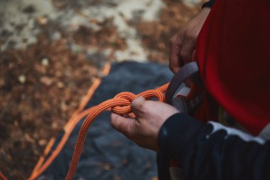 İpi tutan ve dağlara tırmanmaya hazırlanan bir adam. Kaya tırmanış ekipmanları detaylı olarak fotoğrafı kapatın.