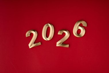 Mutlu yıllar 2026 arkaplan afişi. Yeni yıl kutlamaları için kırmızı zemin üzerinde altın 2026 numara