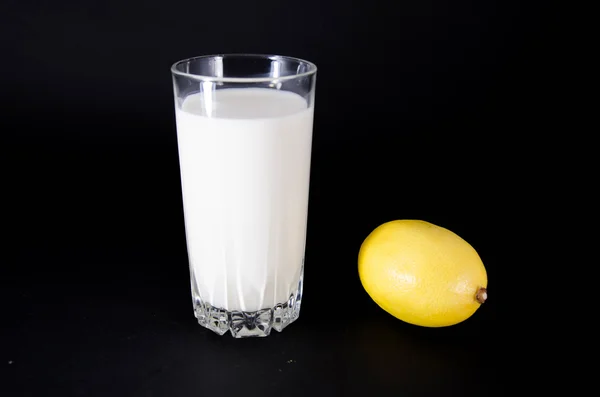 Vaso de leche y medio limón sobre fondo blanco — Foto de Stock