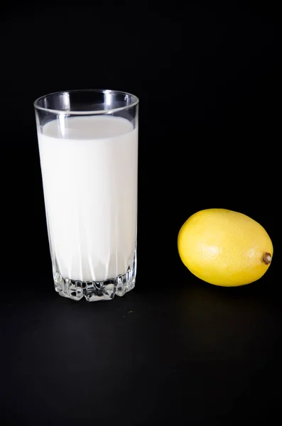 Склянка молока та наполовину лимонних фруктів на білому тлі — стокове фото