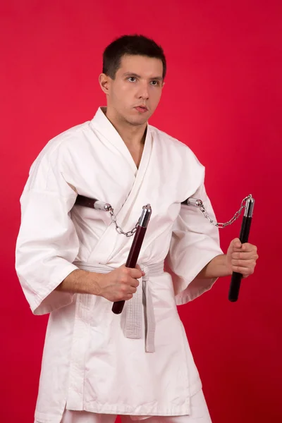 Hombre en kimono practicando artes marciales. Exhibición maestra nunchaku kata . — Foto de Stock