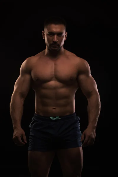 Knappe gespierde bodybuilder poseren op een zwarte achtergrond — Stockfoto