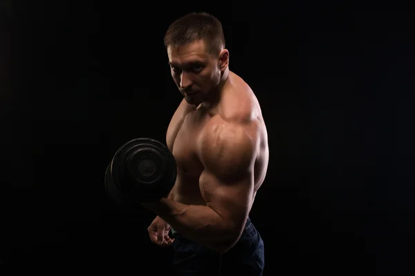 Musculoso bonito fisiculturista posando em um fundo preto — Fotografia de Stock