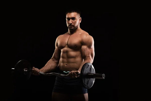 Musculoso bonito fisiculturista posando em um fundo preto — Fotografia de Stock