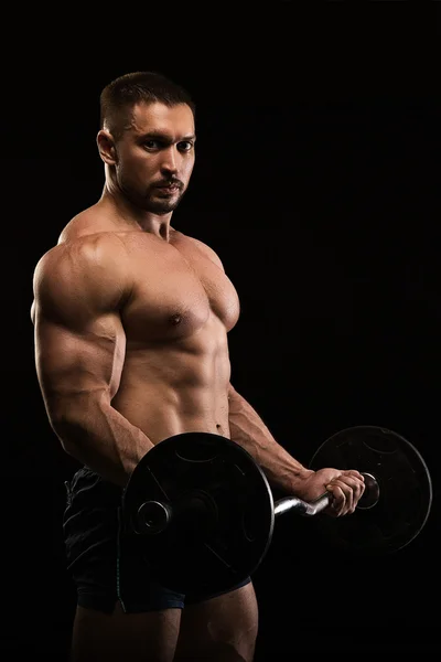 Siyah bir arka plan üzerinde poz yakışıklı kaslı vücut geliştirmeci — Stok fotoğraf